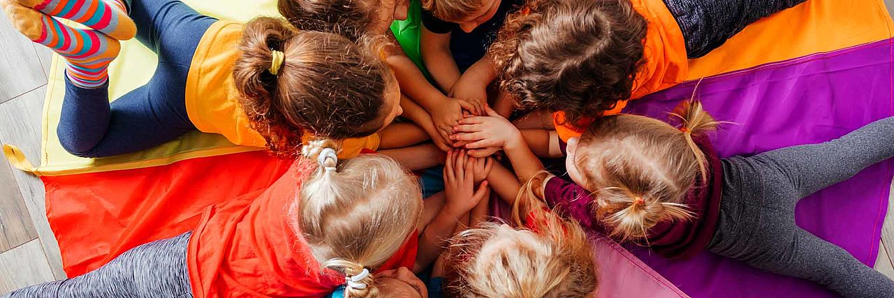BRK Kindergärten im Landkreis Rottal-Inn, spielende Kinder auf einer bunten Matte